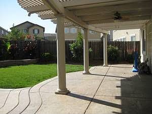 Shaded patio with attached outdoor fan, columns, and stamped concrete