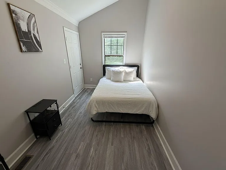 Private bedroom featuring a comfortable bed setup, window for natural light, and closet space with durable flooring.