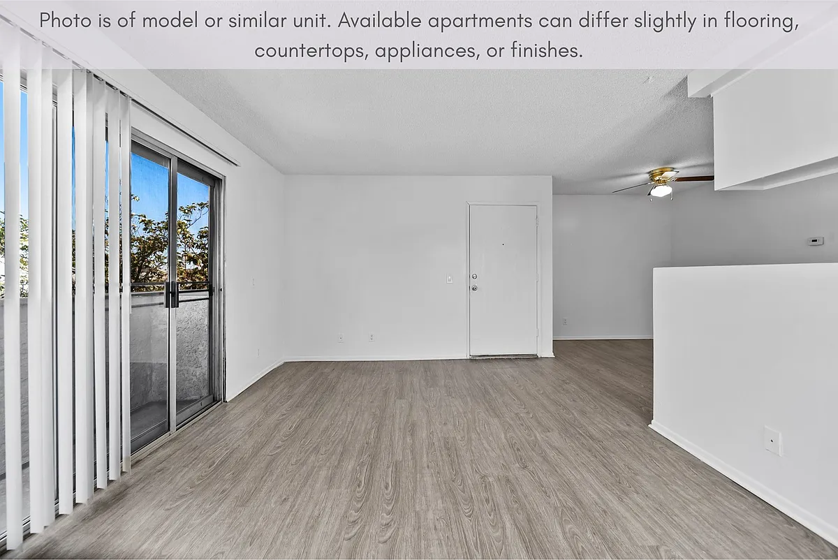 Photo 2 of 10 - Summer Breeze Apartments - Sepulveda, CA Spacious living space featuring natural light and sliding door access to the balcony. - Summer Breeze Apartments