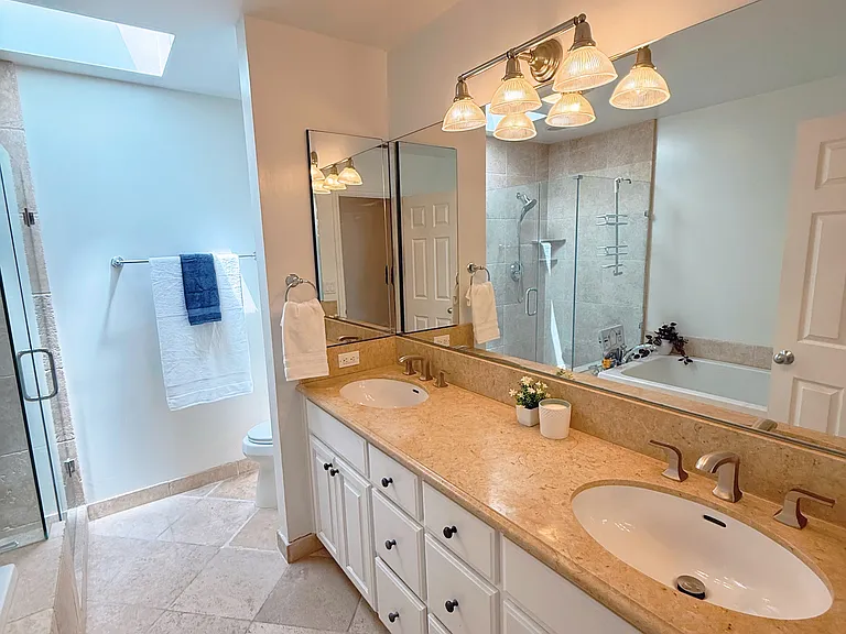Hallway bathroom newerly remodeled with bathtub and shower stall and skylight