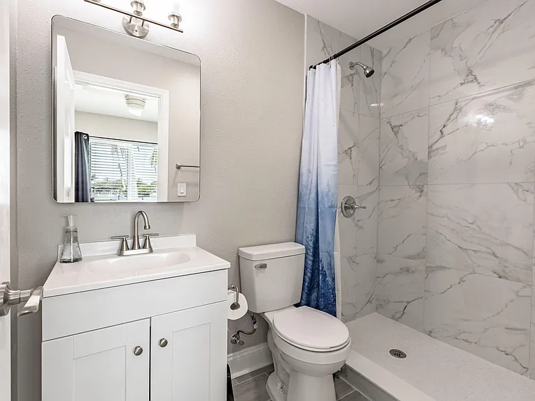 Full bath with tiled walk-in shower, single-sink vanity, and wall mirror with overhead lighting for daily use.