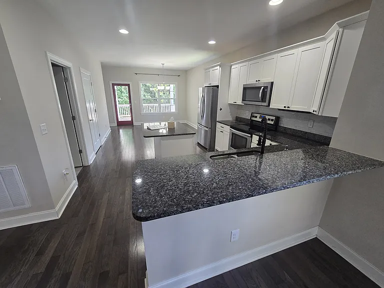 A stunning open floor plan creates an airy and inviting atmosphere, seamlessly connecting the kitchen, dining room, and living room. High ceilings and large windows further enhance the bright, modern feel of this integrated main living area.