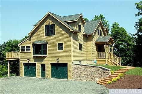 Entry to home with 2 cars below, stoned retaining wall and walkway to covered porch.