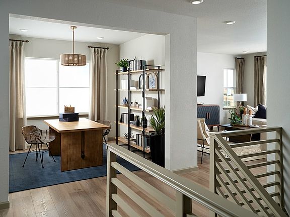 A modern and open-concept living space with a wooden dining table, shelving unit, and a staircase le