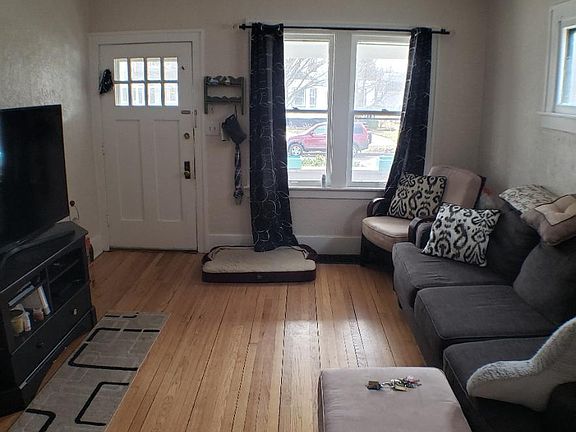 Living room with Entry door as seen looking South from archway to Dining room.