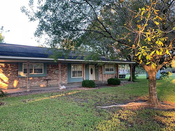 Large Full length front porch with wood swing and mature trees.