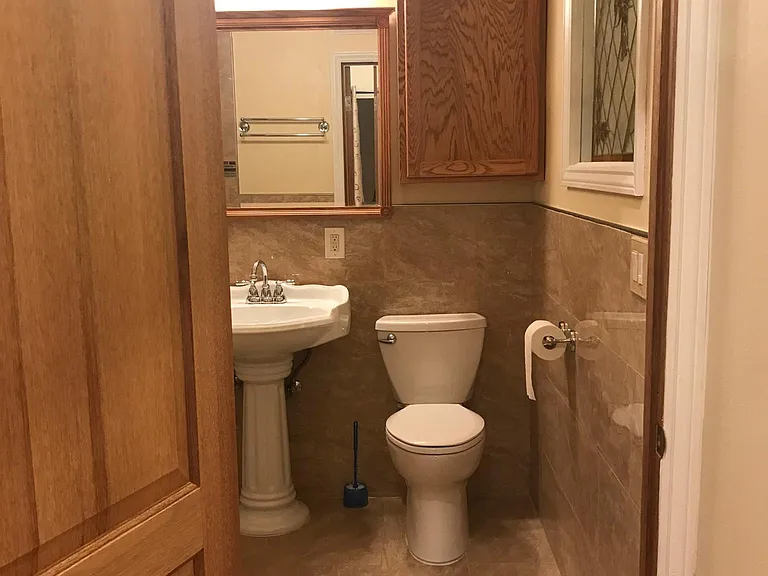 at entry door to bathroom showing tile floors/walls, wall cabinet, sink/mirror and toilet