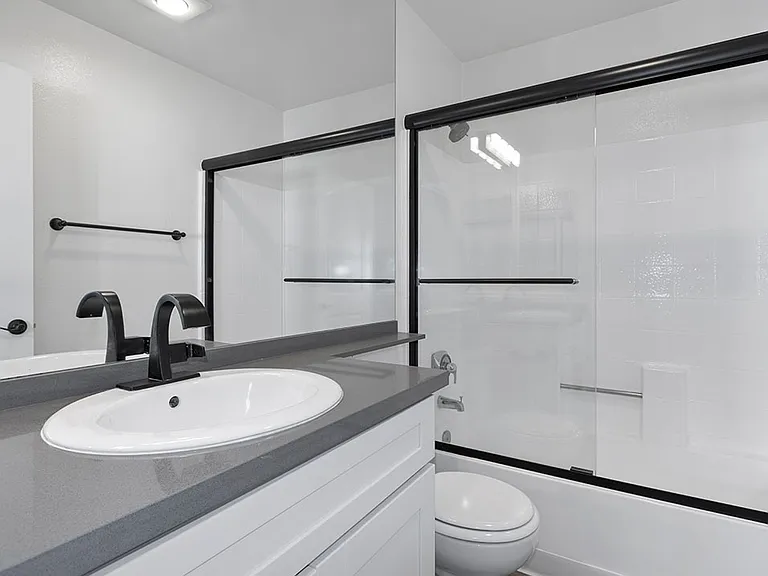 White bathroom with modern fixtures, shower, and tub.