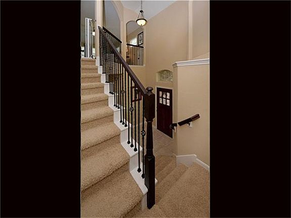A wrought iron staircase with art ledge and landing flows to the  second level.