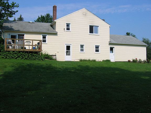 Rear view of house and deck and a small portion of spacious yard