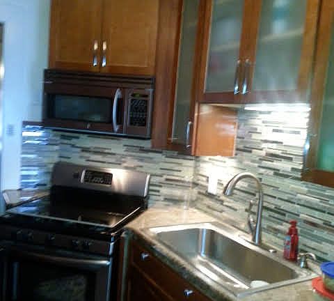 Kitchen includes custom backsplash, undercabinet lighting and stainless steel appliances (microwave, gas stove & oven, dishwasher, and refrigerator).