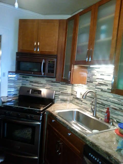 Kitchen includes custom backsplash, undercabinet lighting and stainless steel appliances (microwave, gas stove & oven, dishwasher, and refrigerator).