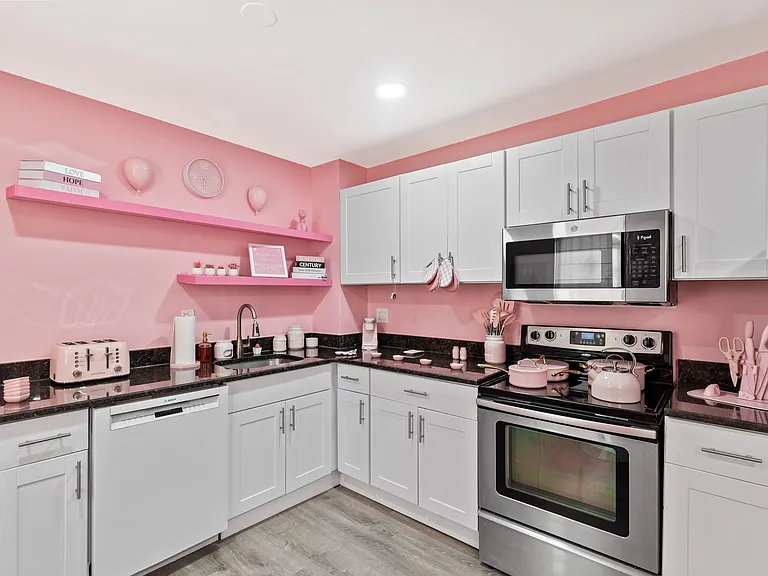 Updated U-shaped kitchen with stainless steel range/microwave, dishwasher, and ample shaker cabinetry for storage.