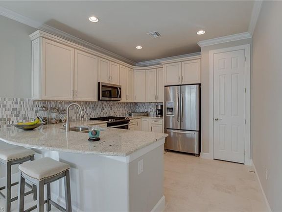 Kitchen with granite countertops, snack bar seating, pantry, stainless appliances and gas range.