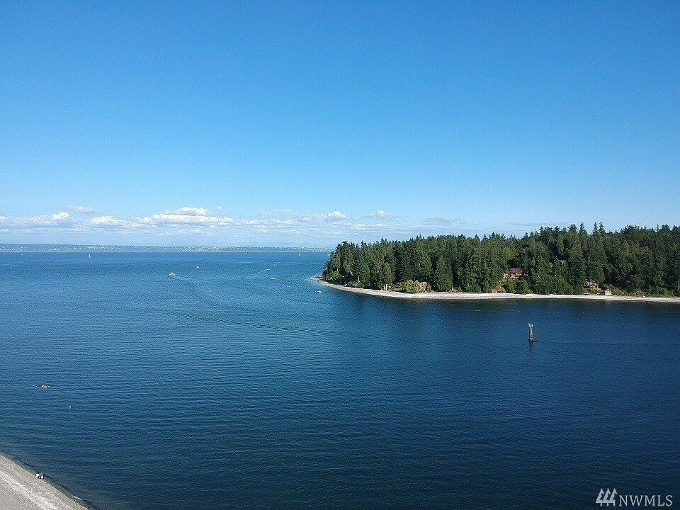 Enjoy the sweeping south facing views of the Agate Passage (which runs between Bainbridge Island and Poulsbo) from the view deck of the home!  Taken on a sunny summer day, this view shows the Cascade Mountains (in the distance to the left of this photo), Bainbridge Island in the foreground) and recreational boats on mooring buoys.  The community beach, which is just a few steps away for easy access to the water, is to the left of this photo