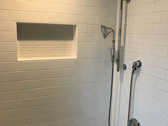 Subway tiled shower and bathtub with rain head and hand held showers.