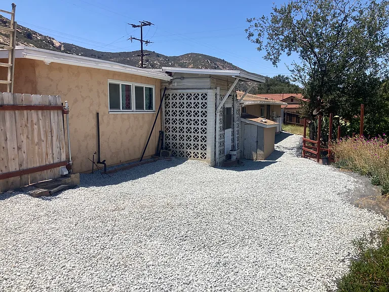 View of the northern face of the house. Hardscaping and a partial metal fence replaced plants, and trees close to the house as part of 'fire-hardening' the house to reduce the risk of catching on fire from a wildfire,