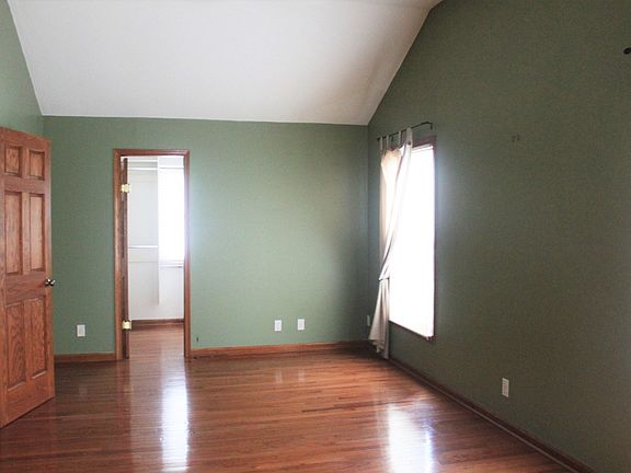 Master bedroom with walk in closet-hardwood floors & vaulted