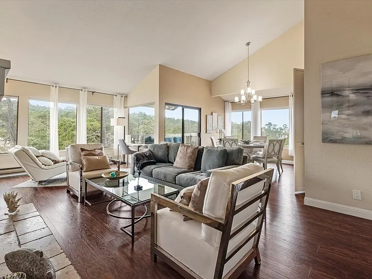 Windows abound in open space living area with 55" smart TV over fireplace.