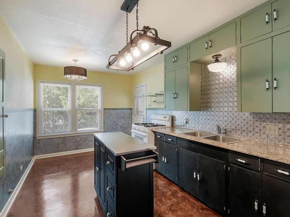 Updated, airy and cheerful eat-in kitchen has plenty of cupboard space, a hanging pot rack, storage/work island, and lots of light