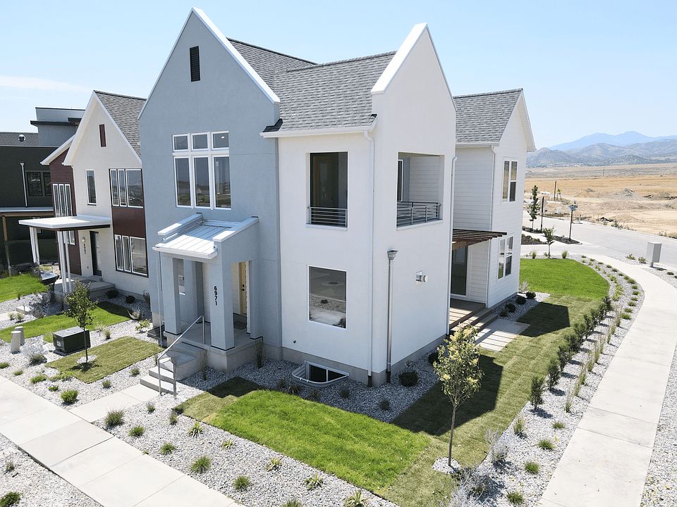 Modern two-story white house with large windows, a small front yard with green grass and young trees