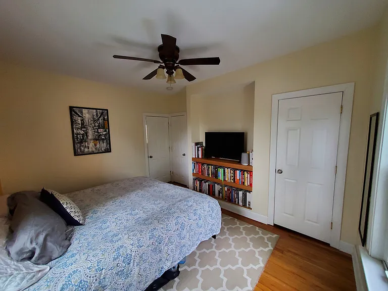 Bedroom 1 is located in the back of the house. King size bed pictured. Ceiling fan in the room. Built in shelves for TV/books. 1 larger closet, 1 smaller closet.