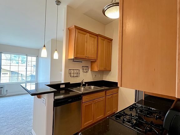 Open layout with kitchen overlooking living room, featuring vaulted ceilings and great natural light