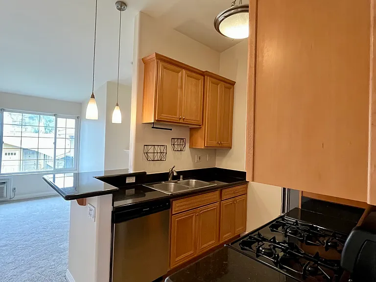 Open layout with kitchen overlooking living room, featuring vaulted ceilings and great natural light