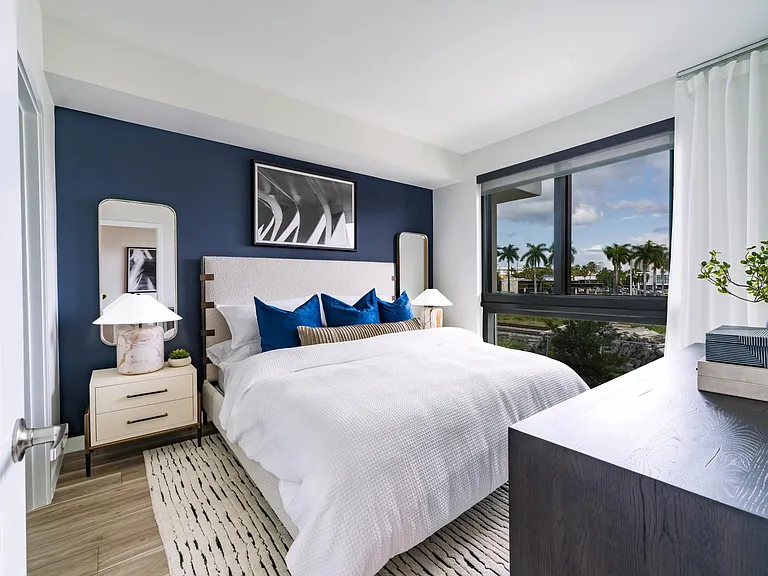 A calming primary bedroom with layered textures and palm-lined views, designed for everyday comfort at Modera Aventura.