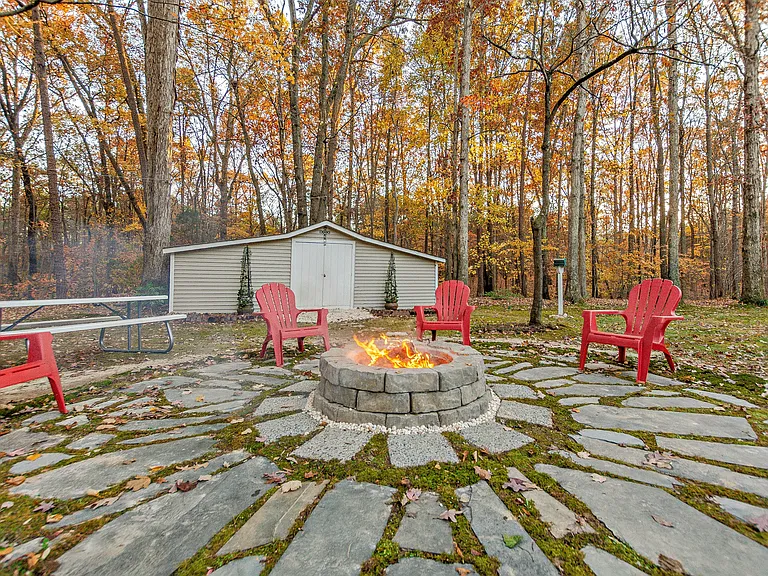 Slate stone fire-ring with Adirondck chairs and moss covered ground.