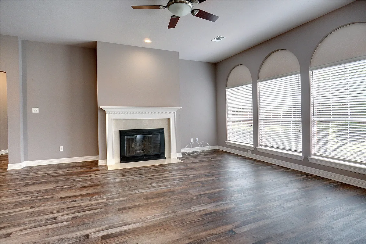 Spacious room featuring wood-finish flooring, a ceiling fan with integrated lighting, and a fireplace with a detailed mantel - 1410 Dartmouth Dr