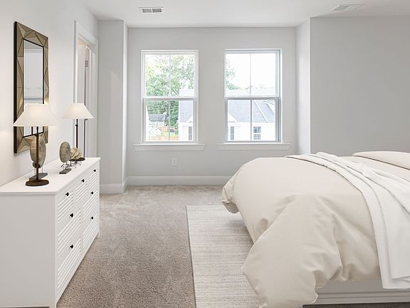 Carpeted owner s suite with two large windows on single wall in a DRB Homes Brookgreen model home at
