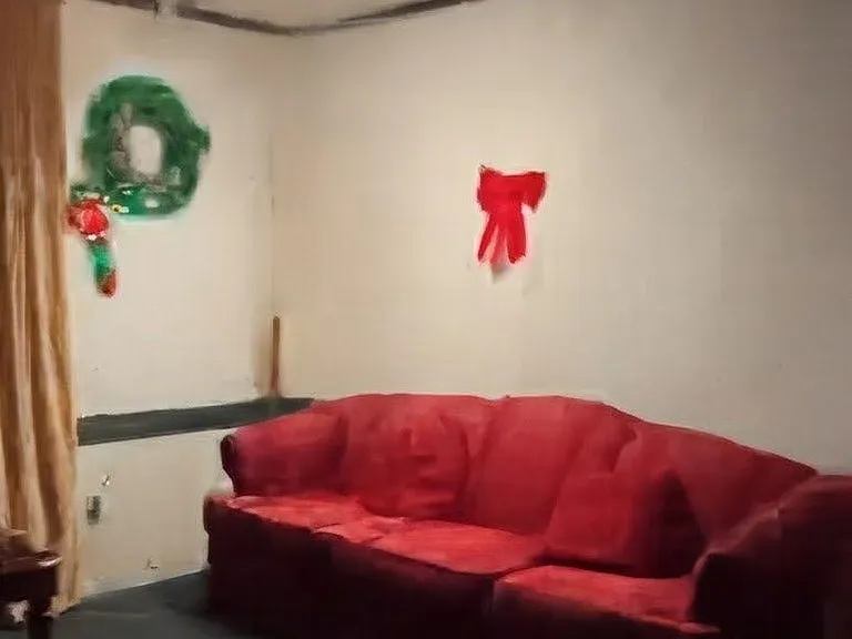 Common lounge area with seating, wall decor, and open floor space for relaxing or gathering with housemates.