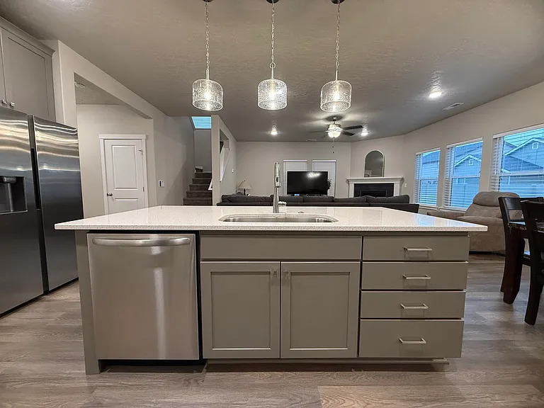 Open-concept kitchen and dining area featuring a large quartz counter top island with seating that overlooks the living room and fireplace.