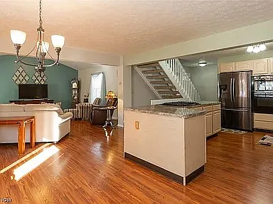 View from Dining Room of Kitchen and Living Room. Open Concept stairwell to basement to the right of the off white couch