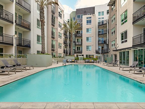 Swimming pool surrounded by poolside cabanas, lounge chairs and tables, and an outdoor fireplace.