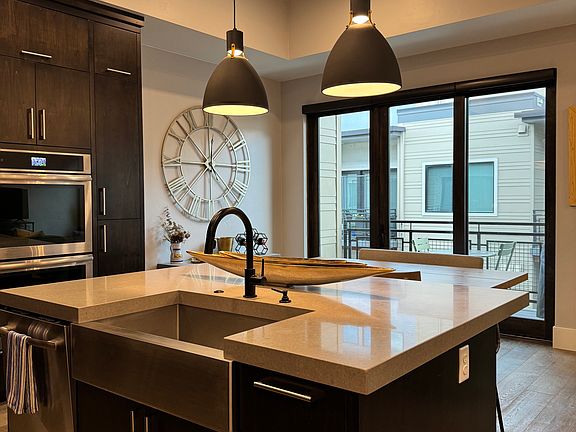 Island in kitchen includes bar stools along with nearby dining table