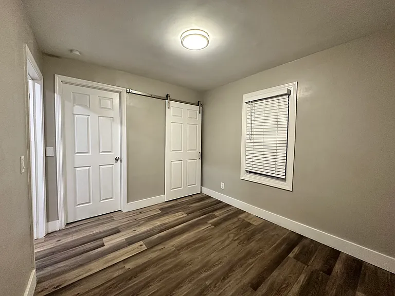 Between closet door and window, there is now a wall installed air conditioning unit.