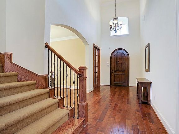 A charming chandelier lights the Foyer as well as an arched window. Notice on the left, the 8-foot double glass French doors that lead to the Study and the massive arch that gracefully leads to the Formal Dining Room.