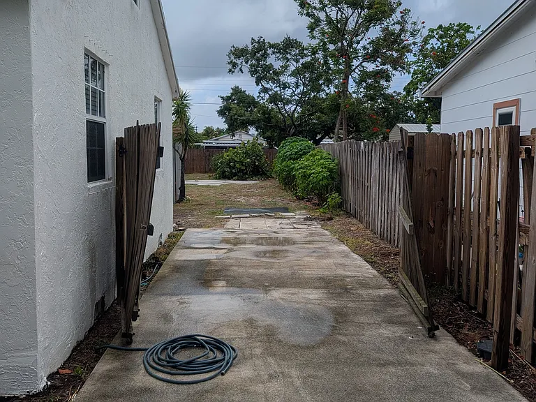 Gate opened showing oversized lot and parking for boat beside house. Recreational Vehicles and/or house trailers not permitted.