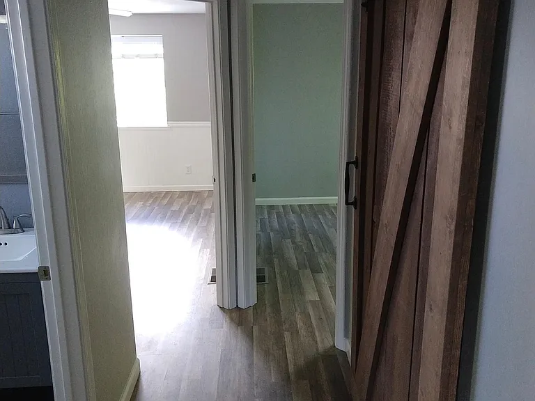 Upstairs hallway to bedrooms and bathroom. Barn door to linen storage closet