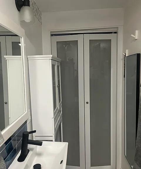 Full bathroom remodeled with new door, mirror, toilet and cabinet for storage.