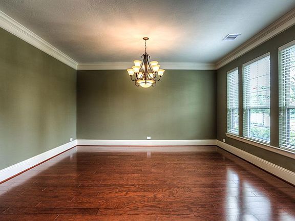 Large dining room with crown mouldings and wood floor.