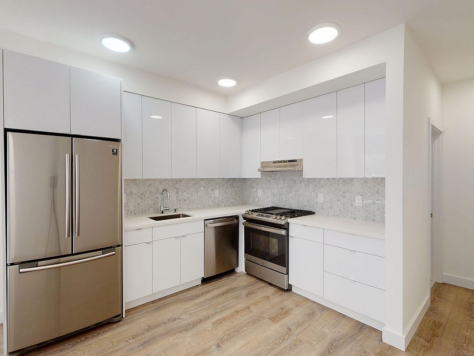 Modern kitchen featuring stainless steel appliances, cabinetry, and wood flooring, illuminated with recessed lighting.