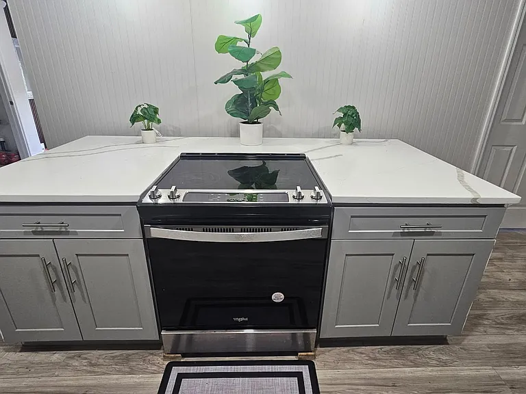 Kitchen features a sleek electric range with expansive quartz-look counters, ample lower cabinetry, and easy-care flooring.