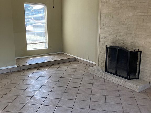 Cozy den with vaulted ceilings, tile floors, and a wood-burning fireplace_a bright, inviting space perfect for relaxing or entertaining.