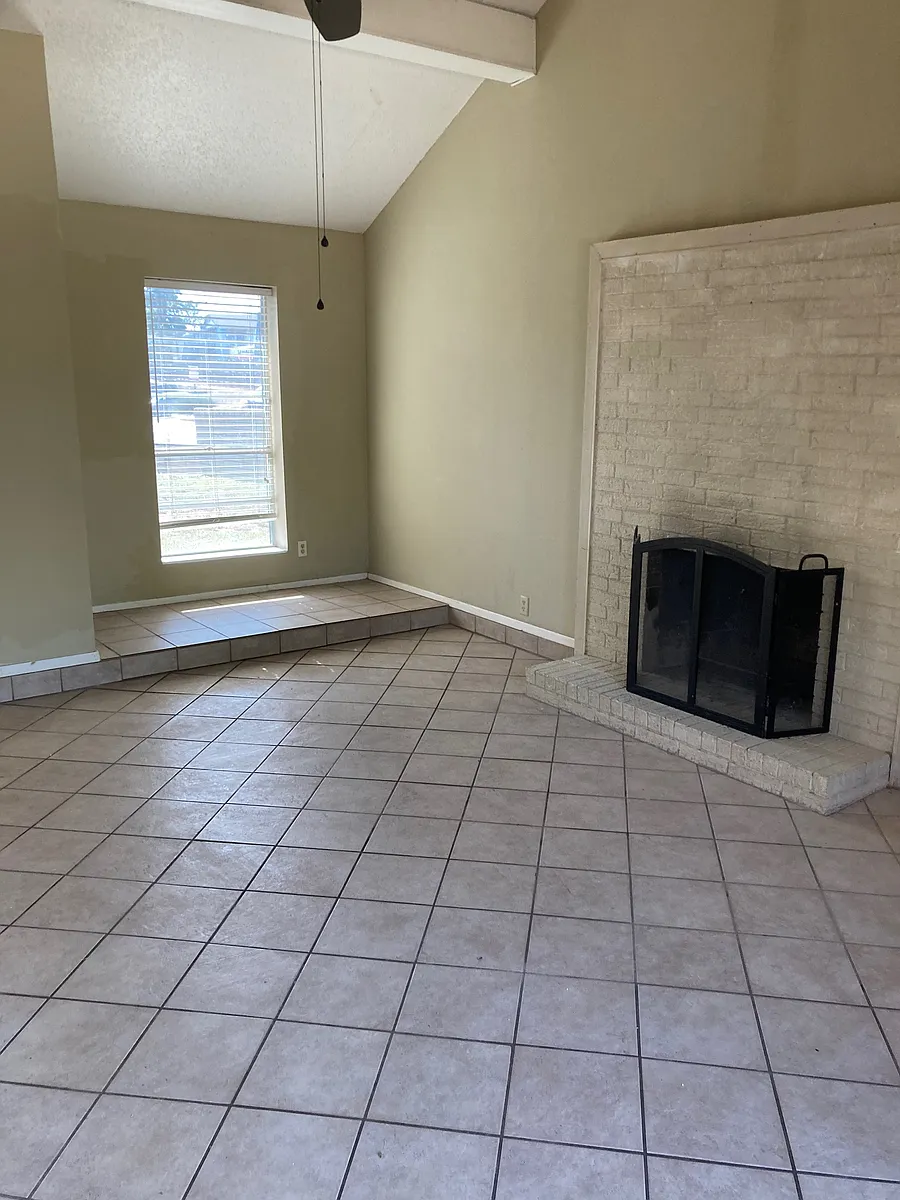 Cozy den with vaulted ceilings, tile floors, and a wood-burning fireplace_a bright, inviting space perfect for relaxing or entertaining. - 2904 Sunset Dr #1