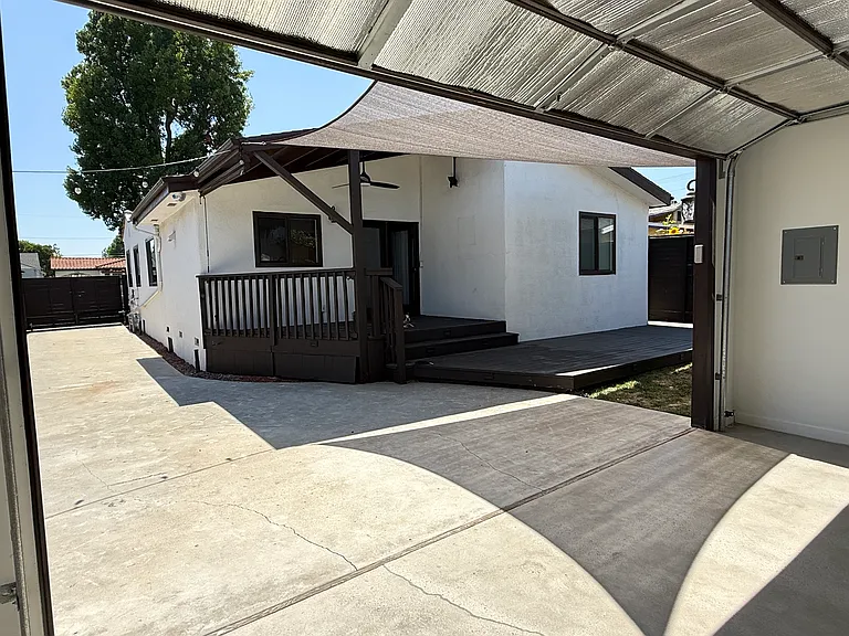 Covered backyard patio with a TV mount, Sunbrella shade, and string lighting. Long private driveway with an automatic remote-controlled gate.