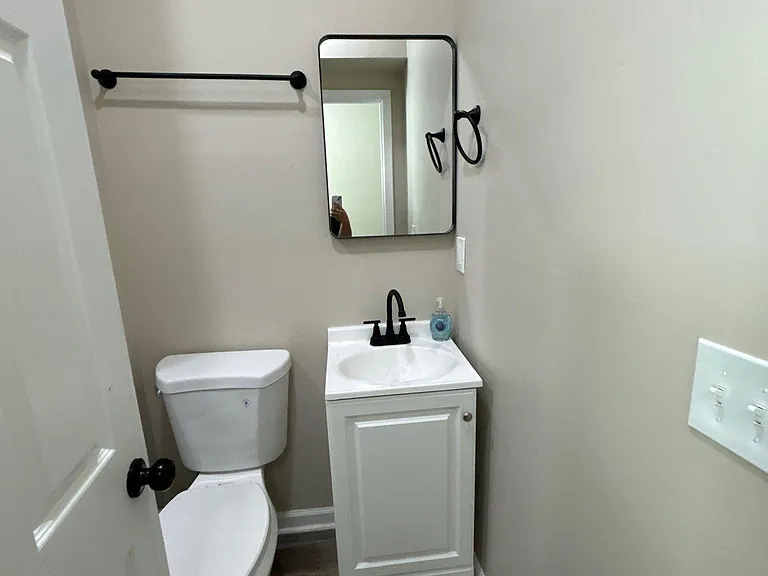 Half bath with pedestal-style vanity, framed mirror, and modern fixturesideal for guest use and quick cleanups.