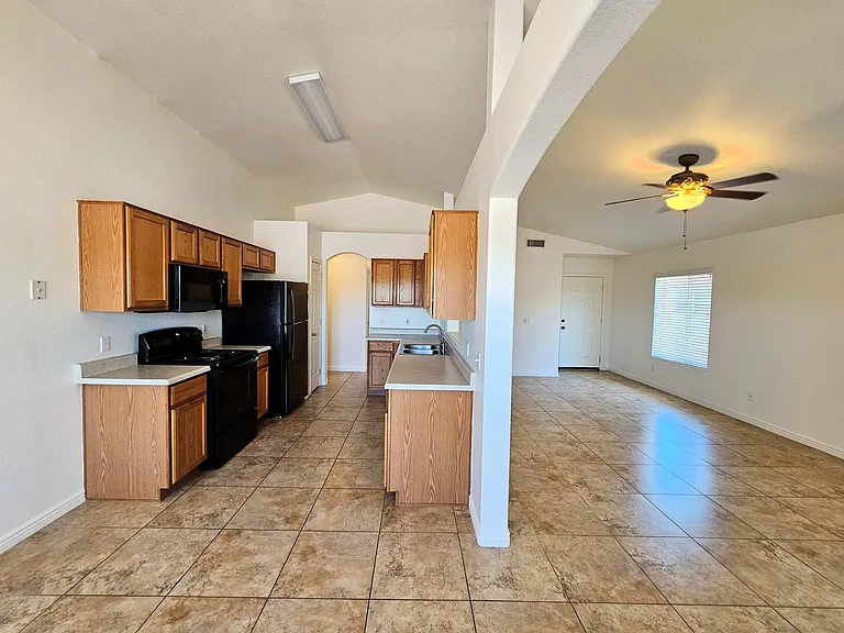 Kitchen has electric range, microwave, refrigerator, disposal, dishwasher and generous cabinets. Large opening leads to living room.
